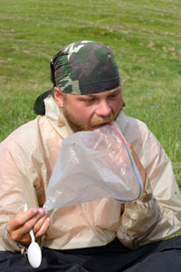 Hungry hiker licking crumbs from a food bag